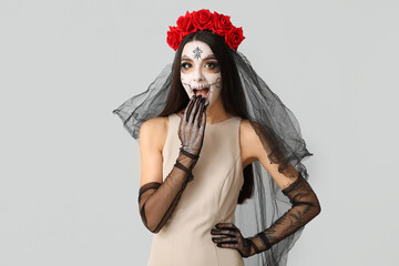 Shocked young woman dressed as dead bride for Halloween party on grey background