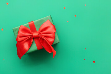 Christmas gift box and confetti on green background