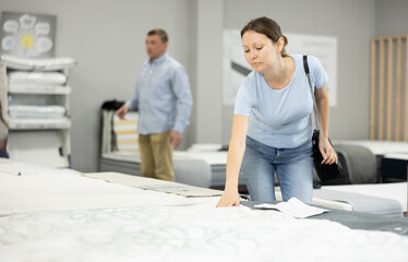 Obraz premium Joyful woman in furniture center chooses best sofa for her apartment