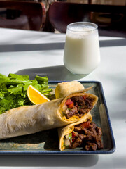 Traditional Turkish Cuisine, Tantuni Kebab, Famous Mersin Tantuni. Tantuni dish taken in sunlight at a restaurant. Meat wrap with arugula, parsley, lemon and ayran.