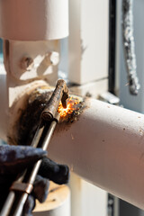 Industrial worker using acetylene torch for cutting metal pipes