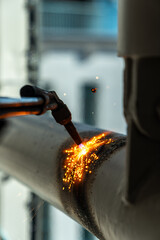 Construction worker using blowtorch welding metal pipe on construction site