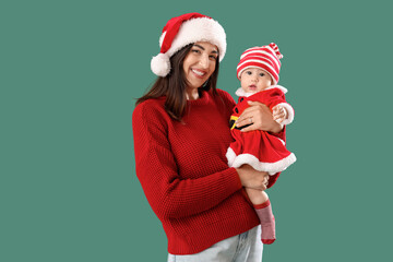 Obraz premium Young mother with cute little baby in Santa Claus costume on green background
