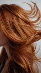 Fototapeta premium Close-up of a woman’s light brown hair flowing in the wind against a simple white backdrop