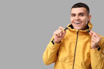 Young man in yellow stylish jacket on grey background