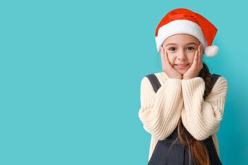 Cute little girl in Santa hat on blue background