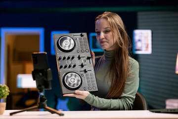 Smiling content creator filming DJ mixing tutorial in home studio, showing examples of sampling on...
