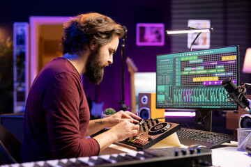 Music producer hitting pre amp knobs to edit soundtracks, mix and master tunes on stereo console in...
