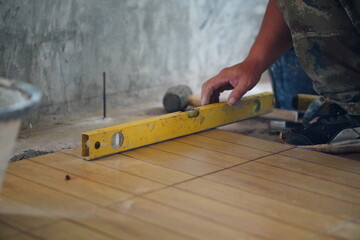 Professional tiling technicians lay floor tiles on the cement surface of the room.