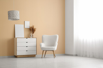 Cozy armchair and chest of drawers near beige wall