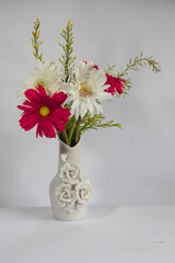Decorative white flower vase with white and red Chrysanthemum flower arrangement, red and white daisy flowers against a white background