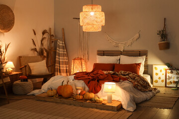 Interior of stylish bedroom with autumn decorations and candles in evening