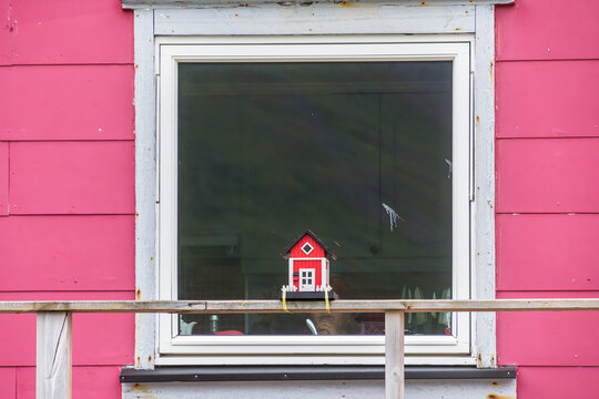 Rotes Vogelh&auml;uschen vor Holzhaus mit Fenster und rosa Holzwand
