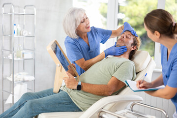 Obraz premium Beautician with nurse talking with patient before injection treatment, while client observing herself in mirror.
