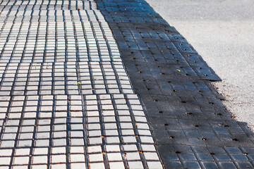 Paving black tiles on the ground in the city. Abstract street background.  Black and white tiled sidewalk featuring a geometric pattern