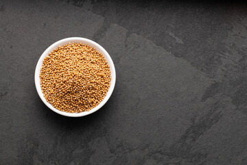 Dried and organic yellow mustard seeds in bowl - Sinapis alba.