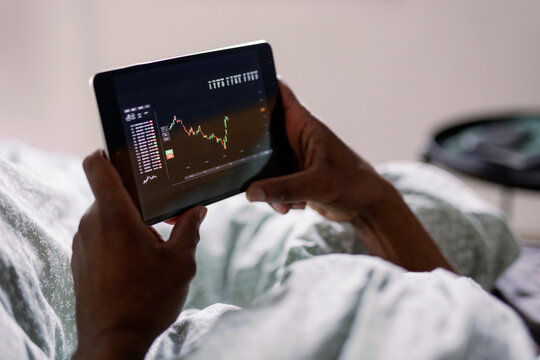 Partial black man watching graph of stock market on digital tablet