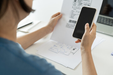 woman use phone scan barcode or QR codes to pay credit card bill after receiving document invoice. payment, receive, paying electricity, digital payments, technology, scanning, financial transactions