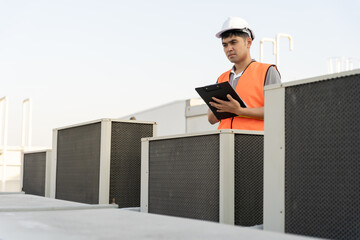Asian maintenance engineer works on the roof of factory. contractor inspect compressor system and...