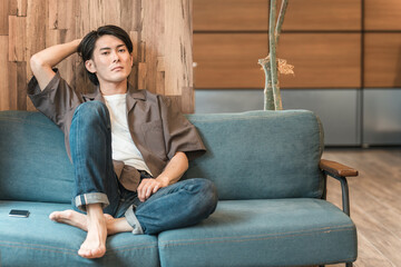 Obraz premium 家のリビングで退屈な時間を過ごす若いアジア人男性（つまらない・憂鬱・無気力・ダルい・疲労・鬱病） 