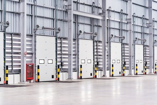 a modern warehouse with a series of loading dock doors, designed for efficient shipping and receiving processes. The warehouse interior is spacious, with smooth concrete flooring that facilitates easy