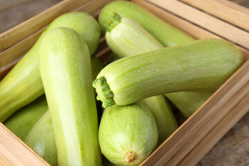 Crate with fresh zucchinis on wooden table, closeup