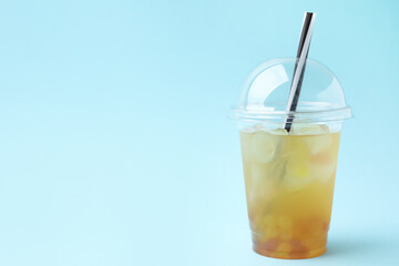 Tasty bubble tea in plastic cup on light blue background, space for text