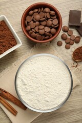 Flour, chocolate and cocoa for making dough on wooden table, flat lay