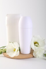 Different deodorants and beautiful eustoma flowers on white background