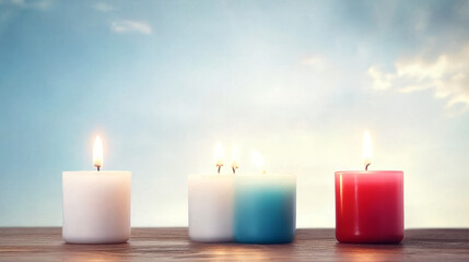 Four candles of different colors are burning brightly against a blue sky.