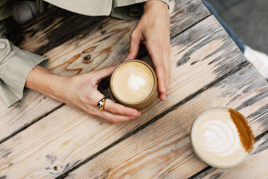 Overhead detailed shot of a woman holding a latte art coffee