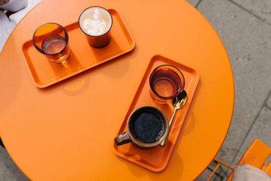 Overhead shot of a couple of coffee drinks served on an orange table