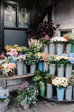 Flower arrangements placed in metal buckets on shelves on the street