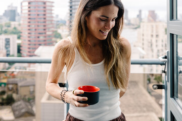 Woman enjoying a cup of coffee from a balcony with views of London