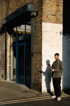 Man uses his cell phone while walking the streets of Dalston, London