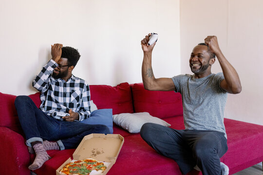Happy man celebrating win on upset friend after playing video game