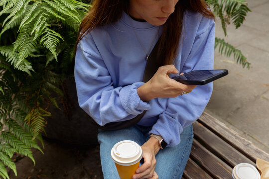 Woman texts on her smartphone while enjoying a cup of coffee