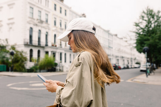 Female traveler typing on her smartphone while walking in Notting Hill