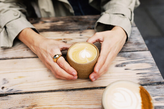 Anonymous woman holding a cup of coffee decorated with latte art
