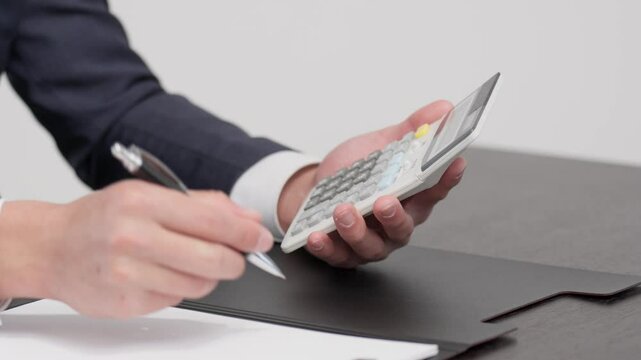 電卓で見積もりを計算するビジネスマンの手元