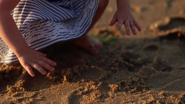 Little girl digging barefoot in the sand on the beach
