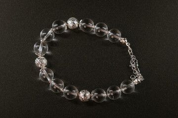 Transparent beads and a metallic ethnic sun bracelet on the black background