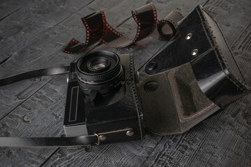 Vintage Film Camera with Leather Case and Exposed Film on Rustic Wooden Background