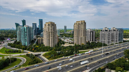 Aerial views of high-rise residential buildings near the 401 expressway and Yonge Street in Toronto. The bustling highway, surrounded by lush greenery and modern architecture, creates a dynamic