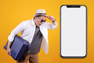 Surprised Traveller Man Wear Hat Carrying Suitcase While Looking to Big Smartphone With Blank Screen