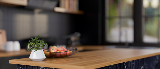 A close-up of a display space on a modern wooden kitchen island in a sleek black kitchen.