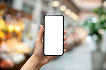 A woman's hand holding a smartphone, set against a blurred background of a market or mall.