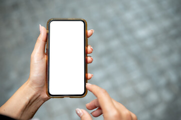 A close-up of a woman's hand holding a smartphone, set against a blurred background of a street.