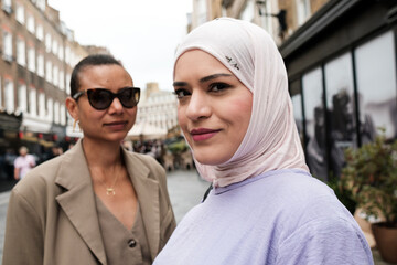 Portrait of two female friends posing in a commercial street.