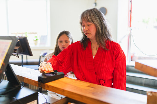 Mother and Daughter Paying with Credit Card at Cash Register